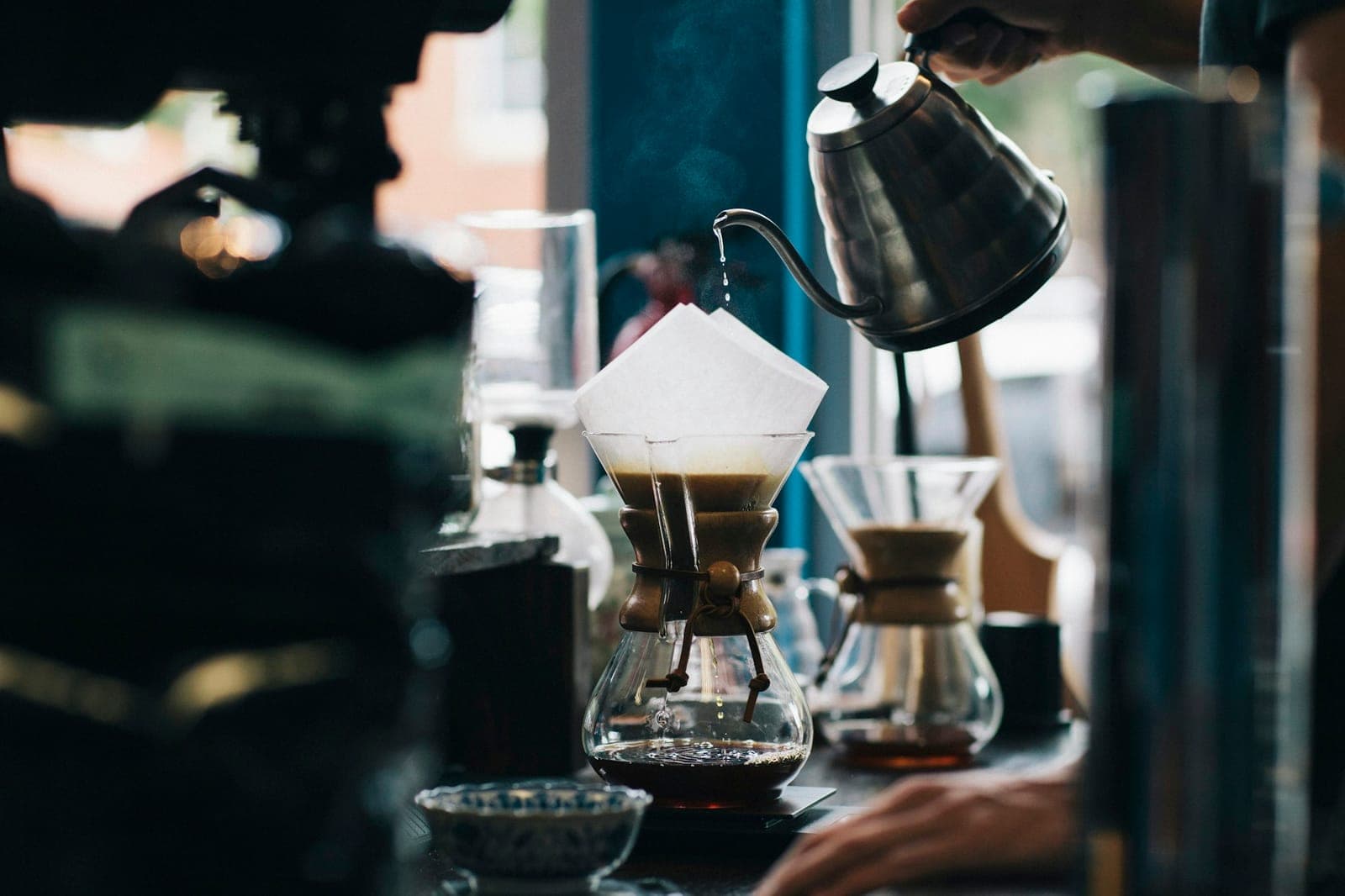 Barista zalewa kawę w Chemexie wodą z czajnika z wąską wylewką